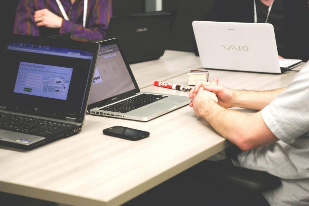 people sitting in a meeting with laptops and markers